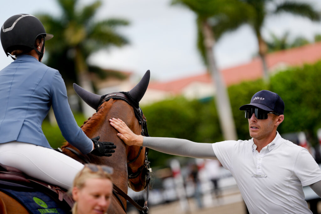 Andrew Welles, wearing an NGP cap, congratulates a rider and horse at a horse show
