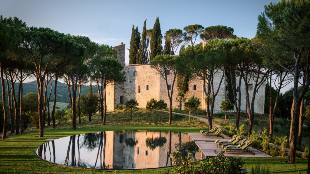 Castello di Reschio's reflecting pool with the restored medieval castle and cypress trees in the background