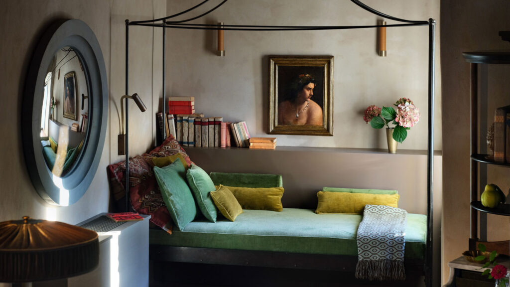 A guest sitting area at Castello di Reschio with a canopy daybed, antique art, and custom Reschio Studio furniture