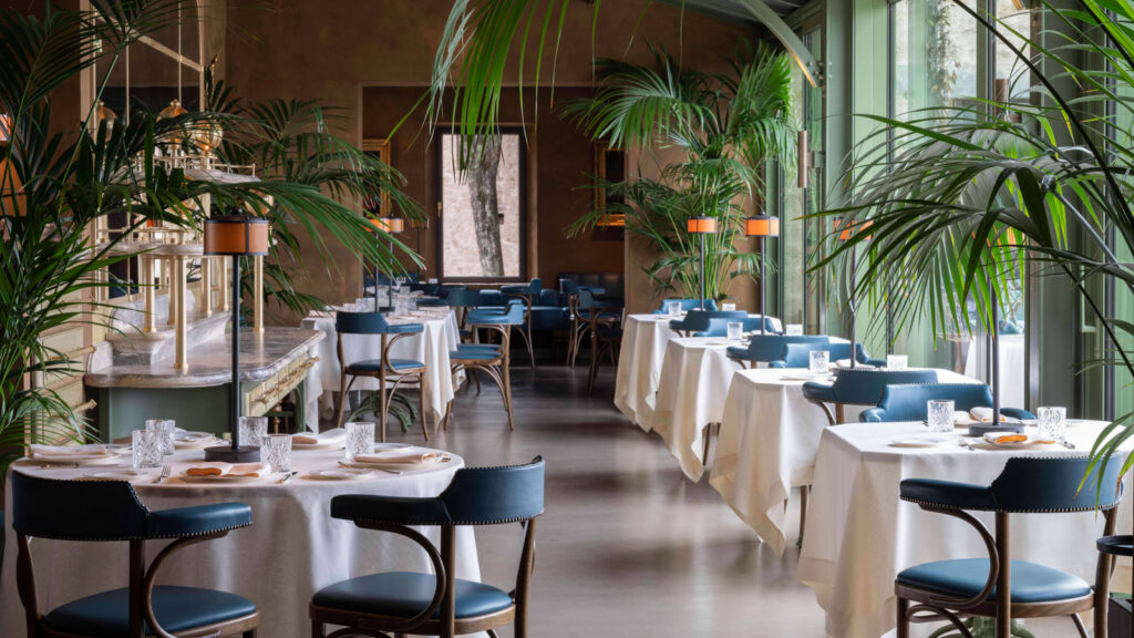 The elegant dining room at Ristorante al Castello, Castello di Reschio, with palm trees and blue leather chairs