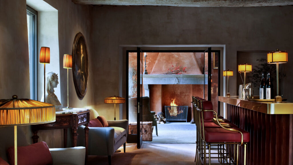 The lounge and bar at Castello di Reschio with a lit fireplace and antique furnishings