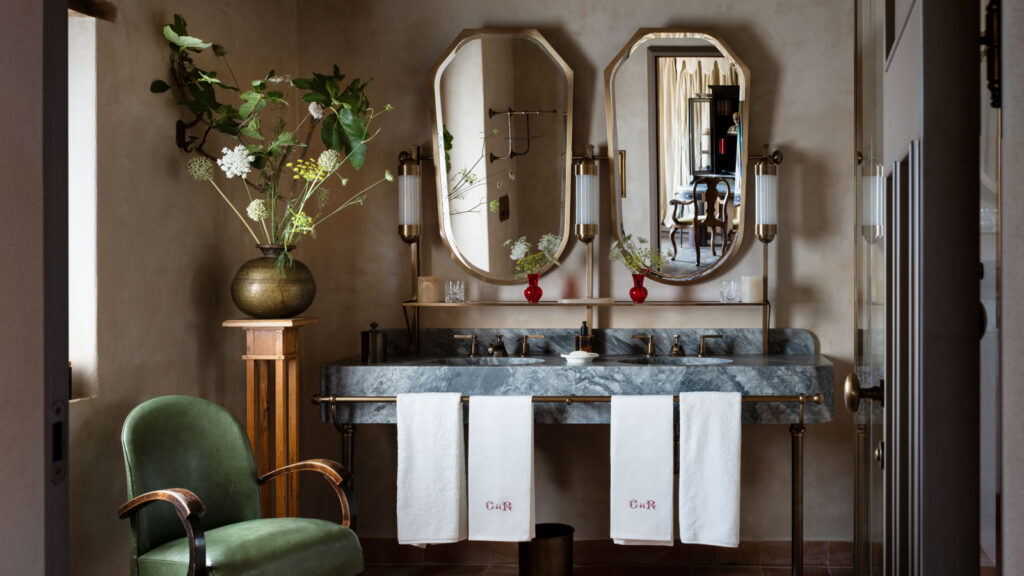 A double marble vanity bathroom at Castello di Reschio with brass fixtures and oval mirrors