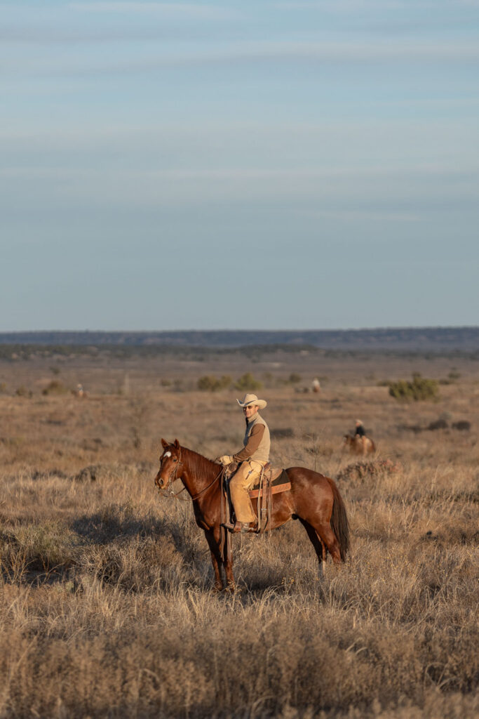 A cowboy on horseback on the open West Texas range